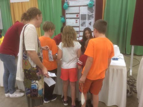 Ye group members presenting around a table to a group of children